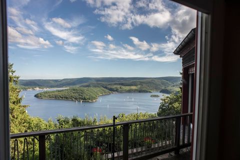 An impressive view of a peaceful lake surrounded by green hills. The mix of sky and clouds creates a relaxed atmosphere.