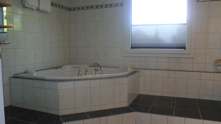 A modern bathroom with a spacious whirlpool and bright tiles. A window provides natural light and a pleasant atmosphere.
