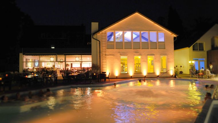 A beautiful pool at night, surrounded by illuminated buildings. Soft lights reflect on the water.