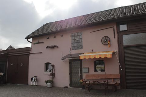 Ein charmantes, pinkfarbenes Haus mit einem gemütlichen Außenbereich. Es hat eine Fensterbank und eine Markise, die zum Sitzen einlädt.