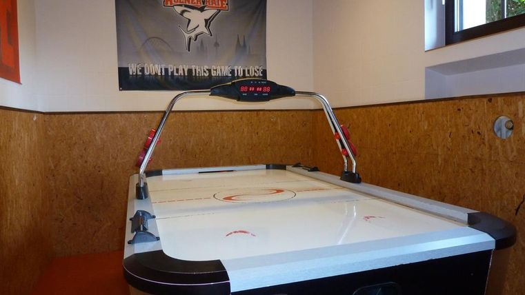 An air hockey table stands in a room with wooden paneling. A banner with the inscription "WE DON'T PLAY THIS GAME TO LOSE" hangs on the wall.