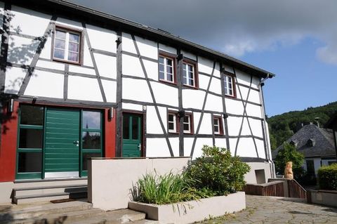A modern half-timbered house with green doors and windows. The entrance area is surrounded by a well-maintained garden landscape.