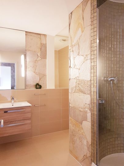 A modern bathroom with a shower and stylish stone tiles. The space is bright and designed in a minimalist style.