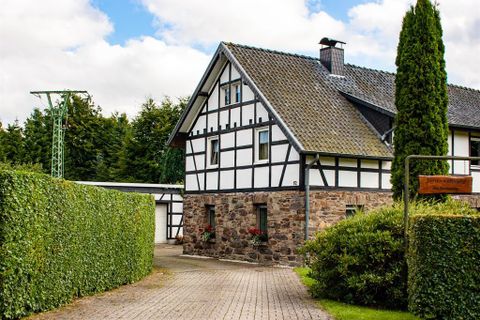 A charming half-timbered house with a paved path.
Surrounded by green hedges and a beautiful garden.