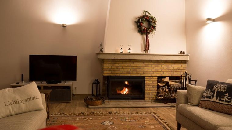 A cozy living room with a fireplace and a television. The Christmas decoration and a warm carpet create an inviting atmosphere.