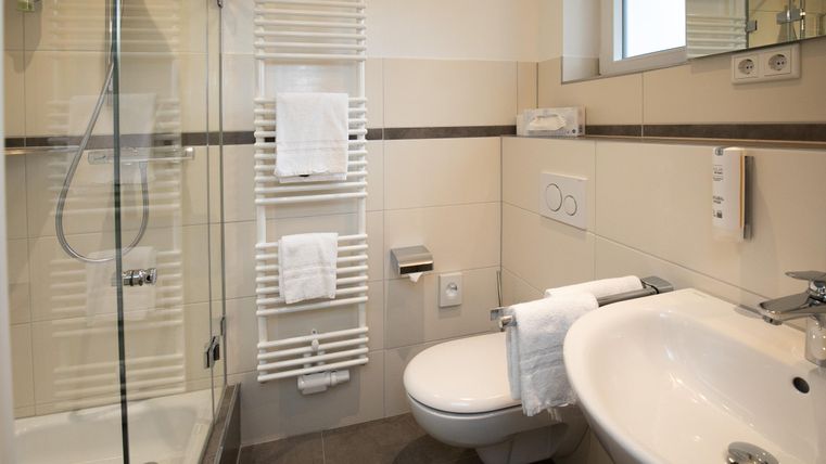 Ein modernes Badezimmer mit Dusche, Waschbecken und Handtuchhalter. Die Wände sind hell und die Ausstattung ist sauber und elegant.