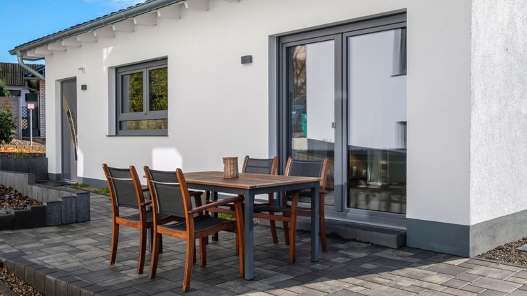 Een modern huis met een buitenruimte. Een tafel met stoelen staat op het terras.