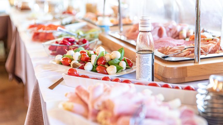 A buffet with various fresh foods, including vegetables, cold cuts, and snacks. The tables are neatly set and inviting.