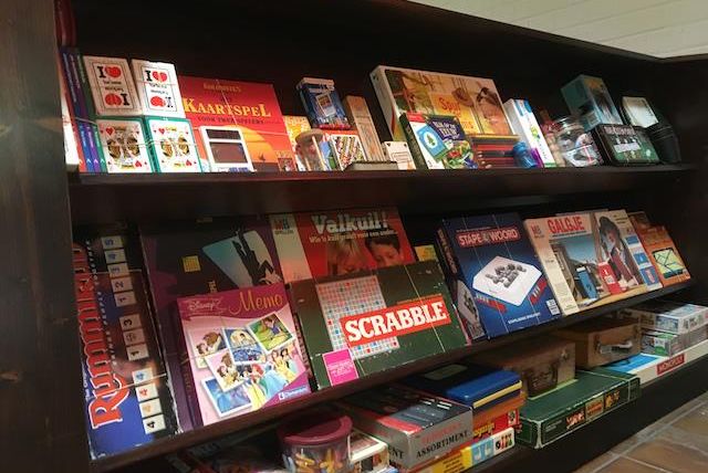 A shelf with various board games and card games. The games are brightly packaged and include classics like Scrabble and Memory.