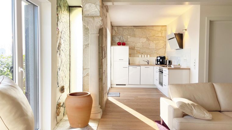 A bright, modern room with an open kitchen corner and a cozy living room. Large windows let in plenty of daylight.