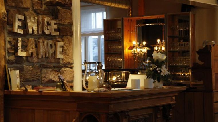 A cozy reception area with a wooden counter and a showcase in the background. On the wall is the inscription "ETERNAL LAMP".
